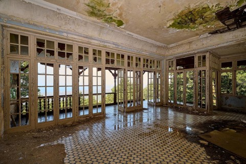 Abandoned room with broken windows, dilapidated floor and view of the green nature, Mussolini