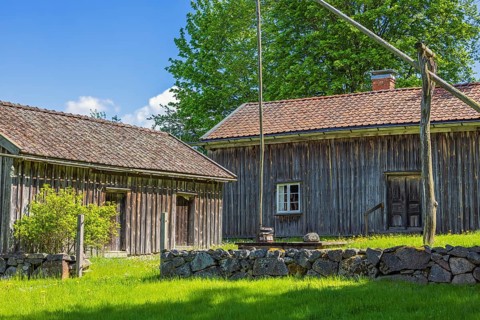 Rustic old farm with wooden house a water well and a stone wall in the swedish countryside, Suntak,