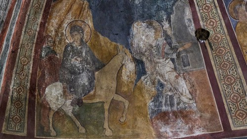 Wall painting showing a holy horseman and an angel in a church, weathered and partially damaged,