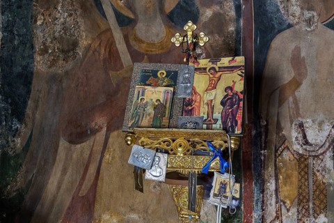 Icons above an ornamented altar in a church, surrounded by other religious symbols and wall