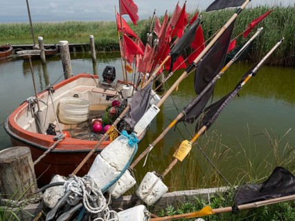 Fishing boat with red and black flags moored in the water, ahrenshoop, zingst, germany