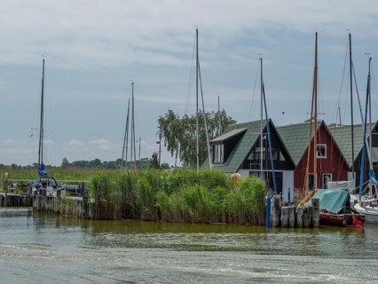 Small boats in front of red harbour houses, canal scene with jetties and reeds, ahrenshoop, zingst,