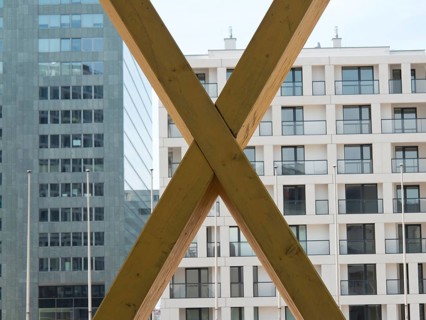 X-shaped timber constructions in front of a modern office building with large windows, Vienna,