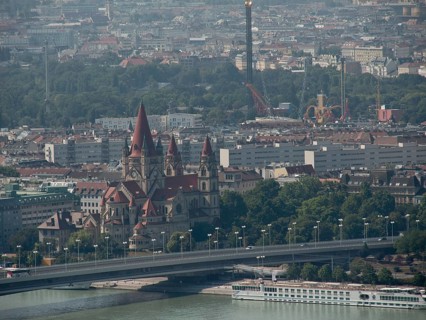 Historic church with striking towers in the middle of a dense urban landscape and a bridge over the