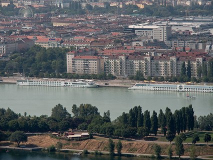 Panorama of a city by the river, lined with trees and large residential buildings in the