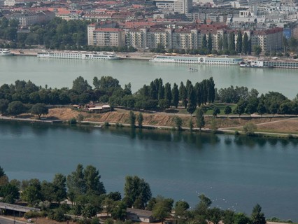 View of a riverside town with park-like areas, trees and residential buildings in the background,