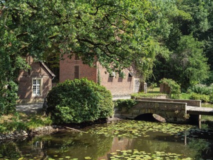 Rural idyll with a pond full of water lilies and a charming stone bridge flanked by old brick