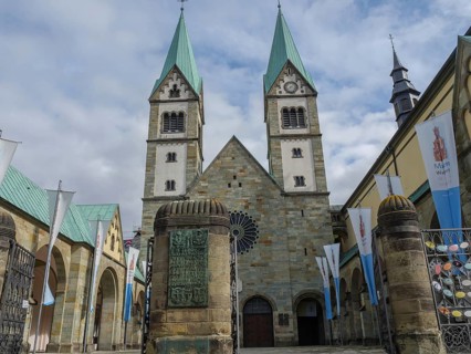 Imposing church with twin towers and main entrance, banners waving against the cloudy sky, Werl,