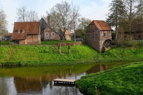 Idyllic landscape with traditional farmhouses and green lawns by a stream, Vreden, North