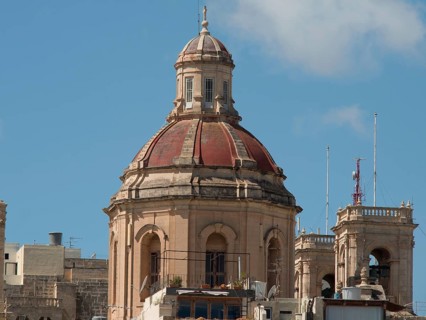 A historic church tower with a domed roof rises up under a blue sky, valetta, mediterranean sea,
