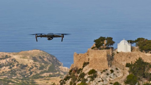 Drone flies over a castle ruin with chapel on a rock in front of the wide sea, Chapel of Saint