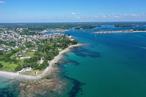 Aerial view of the coast of Loctudy with villas and lighthouse Phare de Langoz, behind Ile-Tudy,