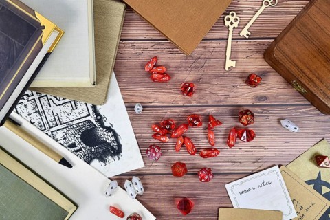 Tabletop role playing flat lay background with red RPG dices, rule books and notes on wooden