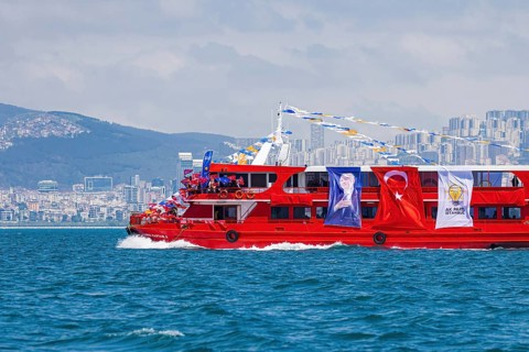 Supporters of the ruling AK party waving turkish flags on a red boat before presidential elections