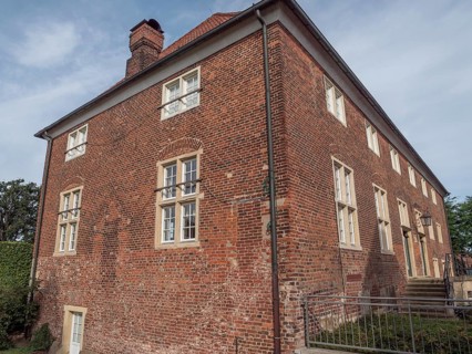 Large, two-storey brick building with many windows and a chimney under a cloudy sky, ramsdorf,