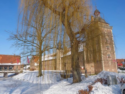 Castle in winter, next to a large willow tree, surrounded by snow and a clear blue sky, Raesfeld,