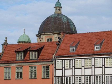 Historic buildings with red tiled roofs and a large dome under a partly cloudy sky, Gdansk, Poland,