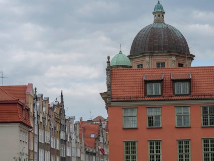 Historic city buildings with striking domes and tiled roofs under a cloudy sky, Gdansk, Poland,