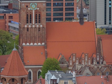 Brick church tower against a backdrop of modern architecture and skyscrapers, Gdansk, Poland,
