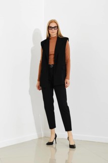 Stylish professional woman in chic black vest, terracotta sweater and tailored trousers, standing