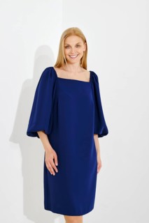 Medium closeup portrait of cute cheerful woman wearing blue dress with balloon sleeves on white