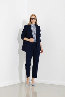 Professional woman stands confidently against a white wall, dressed in a chic navy blue business