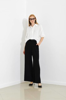 Stylish modern woman in loose black trousers and white shirt paired with glasses and leather