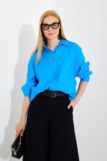 Medium closeup portrait of cute woman wearing blue button down shirt and maxi skirt on white