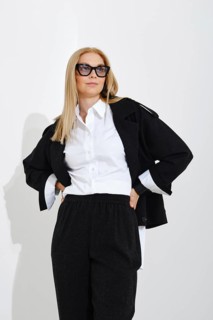 Bottom view of a confident modern woman in a classic suit holding her hands on her waist and