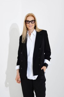 Medium closeup studio portrait of cute blonde woman in white shirt, black jacket and trousers
