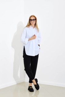 Urban-style fashion portrait of happy smiling woman wearing white shirt and black trousers.
