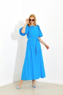 Dynamic full-length portrait of a woman in a bright blue dress and matching shoes against a white