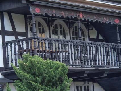 Close-up of a half-timbered house with detailed wooden railings on the balcony and black