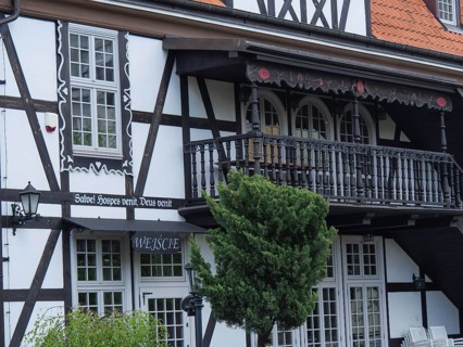 Detailed view of a half-timbered house with an ornately decorated balcony, large windows and green