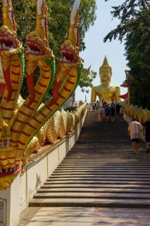 Golden Buddha statue at the top of a wide staircase, flanked by golden dragon figures, Pattaya,