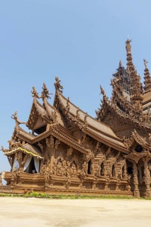 Close-up of a wooden temple with rich sculptures and reliefs, blue sky in the background, Pattaya,