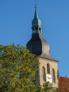Close-up of a church tower with a clock and green dome in front of a blue sky, nottuln,