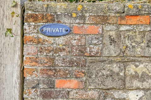 Red brick wall with 'private' sign on it