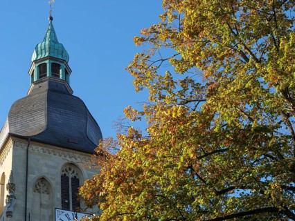 Church tower rises into a clear, sunny autumn sky, surrounded by colourful leaves, nottuln,