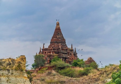 Brick stupa with behind green trees at the Irrawaddy river