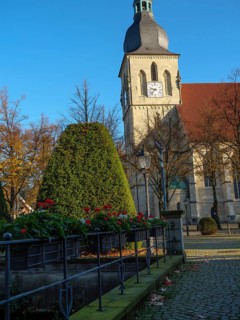 Historic church with clock on the tower, surrounded by an autumn garden and flowers, nottuln,