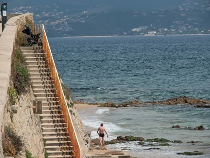 A man walks down to the beach via a coastal staircase overlooking the sea, ajaccio, corsica, france