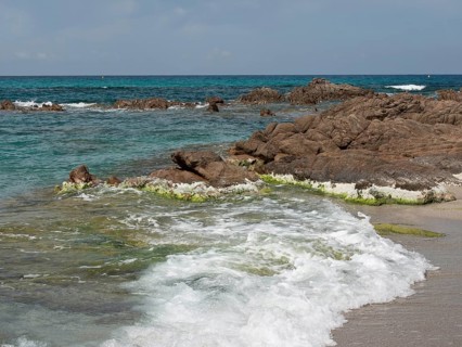 Sea waves crashing against a rocky shore, with seaweed in the water, ajaccio, corsica, france