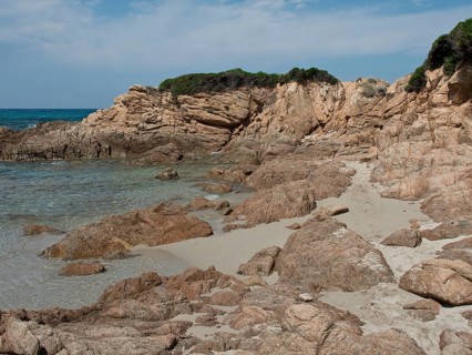 Rocky coastline with a strip of sand and dense vegetation bordering the sea, ajaccio, corsica,