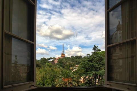 Vatican gardens seen through a window of the museum with a reflection of the basilica
