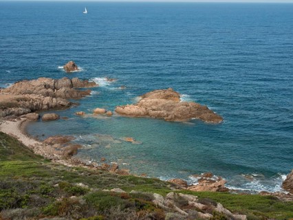 Clear blue water lapping various rocks along the coast under an expansive sky, ajaccio, corsica,