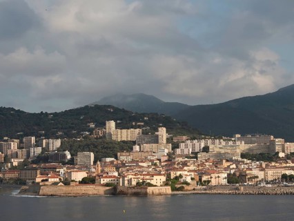 Coastal town with many buildings, mountains in the background and sunny sky, ajaccio, corsica,