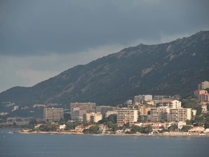 City on the coast with mountains in the background, partly cloudy sky and many buildings along the