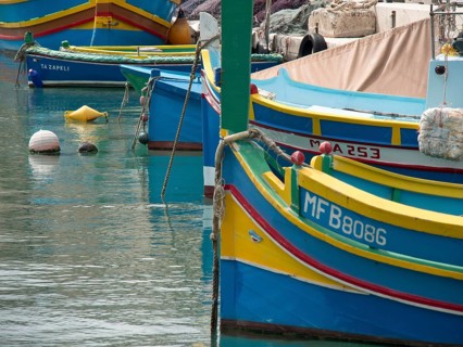 Colourful boats moored close together in a harbour, with ropes and buoys, marsaxlokk, mediterranean