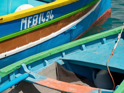 Close-up of several colourful boats lying in the water of a harbour, marsaxlokk, mediterranean sea,